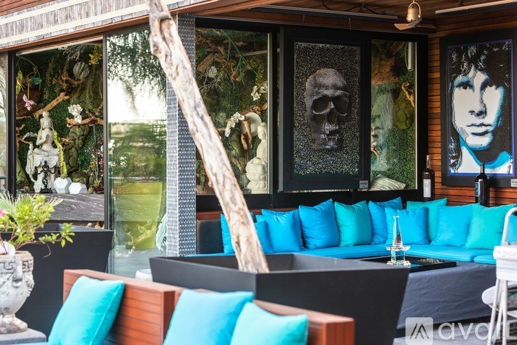 A room with a blue couch and a skull picture on the wall.