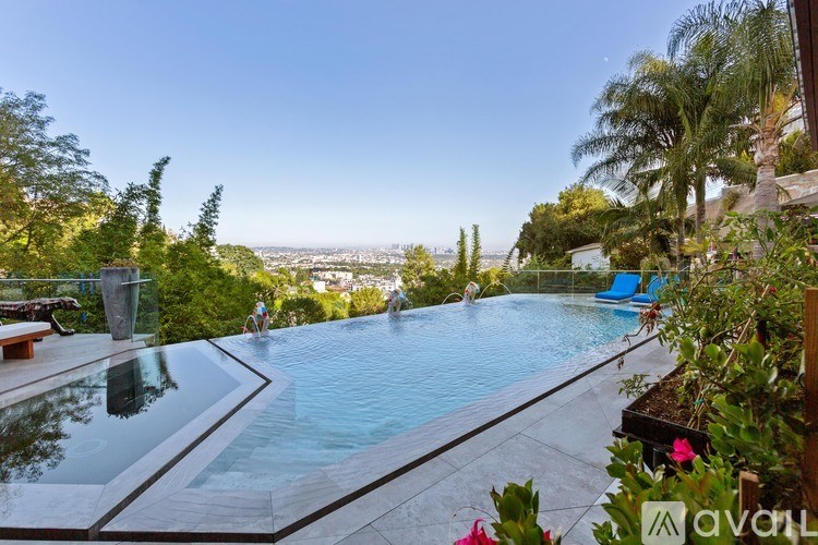 A swimming pool with a glass barrier and a view of the city in the distance.