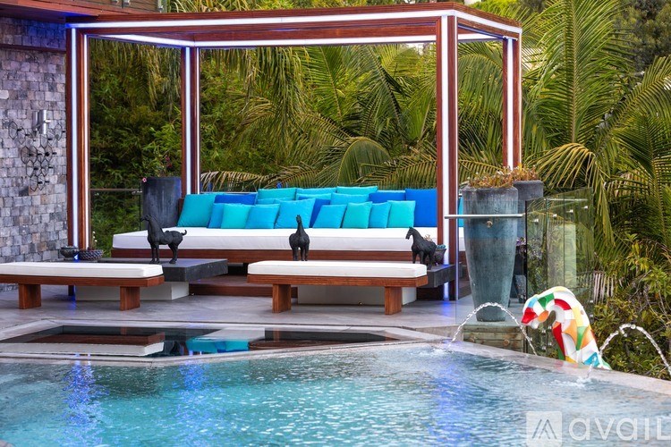 A pool with a waterfall and a bench with a blue cushion.
