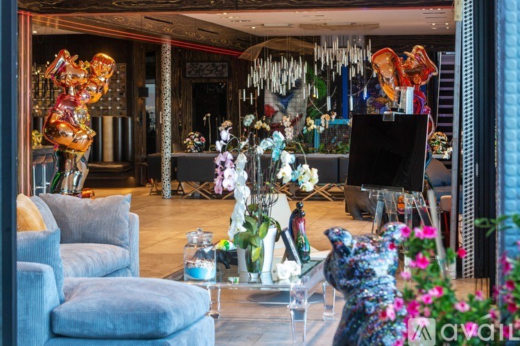 A living room with a grey sofa and a glass coffee table with a vase of flowers on it.