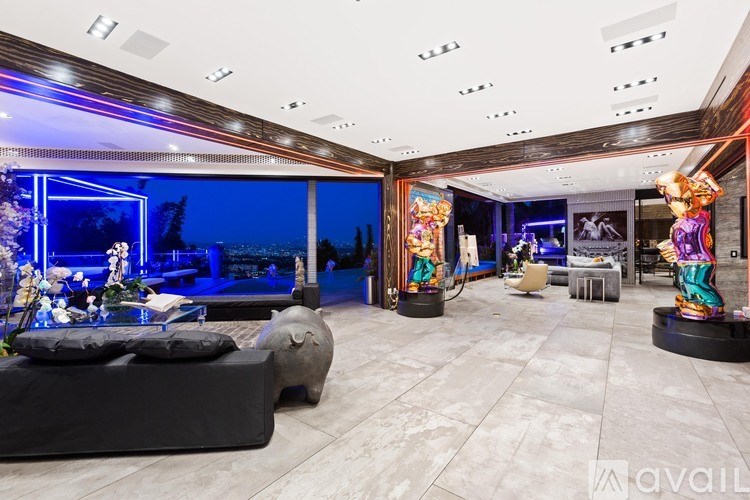 A modern living room with a black couch and a large window.