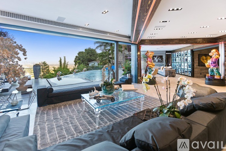 A modern living room with a pool table and a view of the trees outside.
