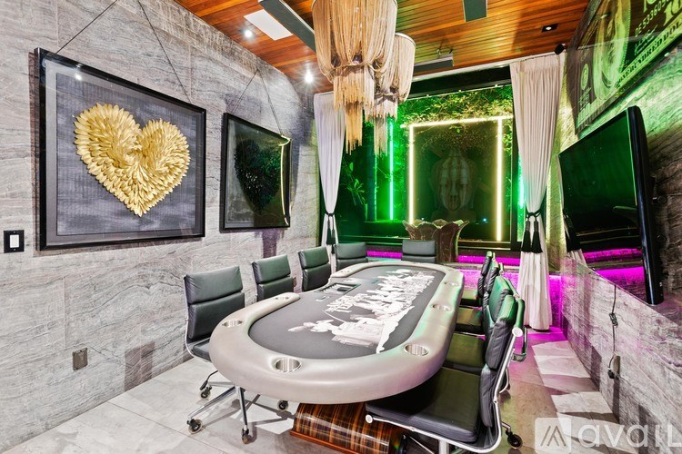 A poker table is surrounded by chairs in a room with a green light.