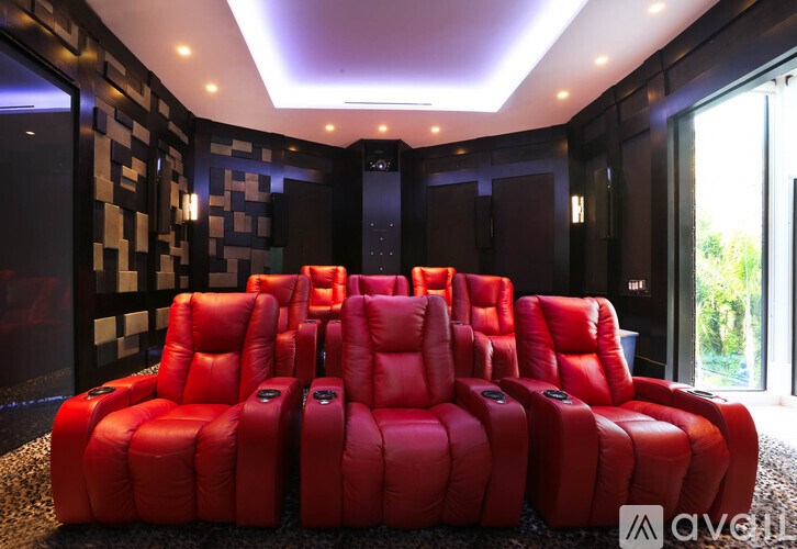 A row of red leather recliner chairs are lined up in a dark room.