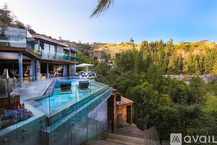 A modern house with a pool and a view of the forest.