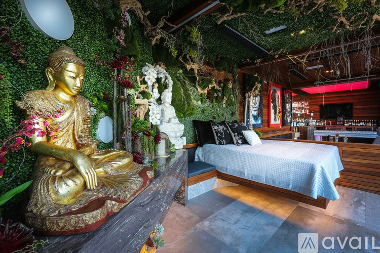 A golden Buddha statue sits on a bench in a room with a bed and a green wall.