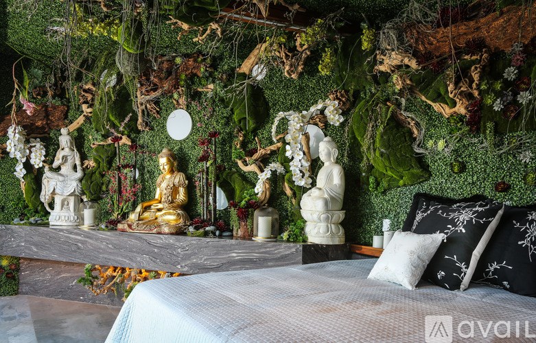 A bedroom with a bed in the foreground and a wall covered in greenery and statues.
