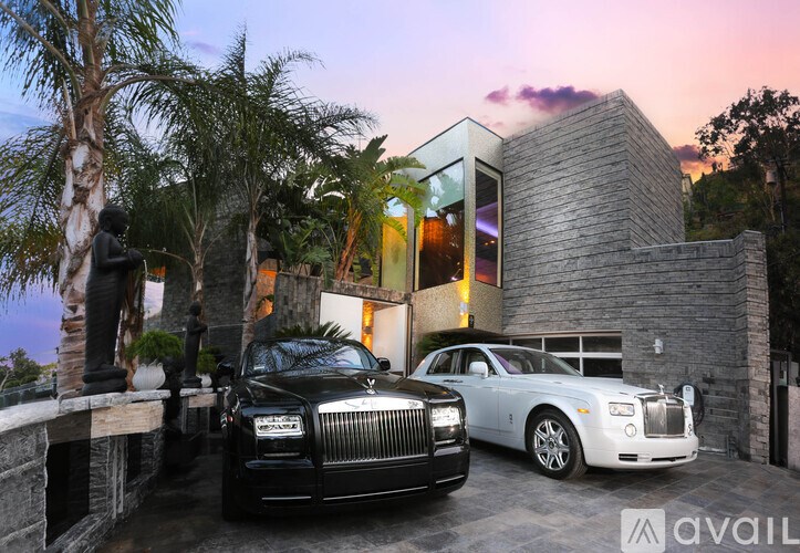 Two luxury cars parked in front of a modern house.