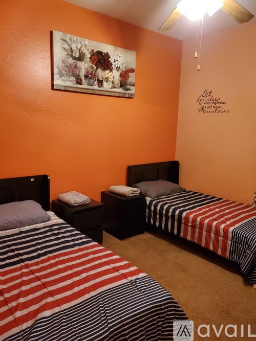 A bedroom with two beds and a painting on the wall.