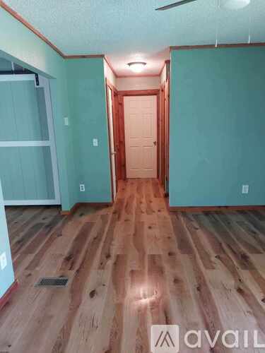 A room with wooden flooring and a door in the middle.