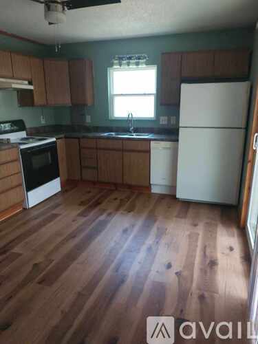 A kitchen with wooden floors and white appliances.