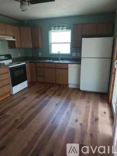 A kitchen with wooden floors and white appliances.