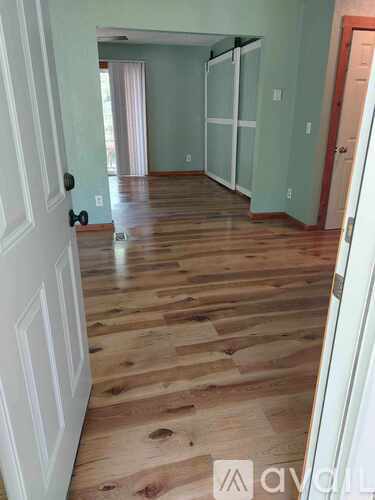 A hallway with wood flooring and white walls.