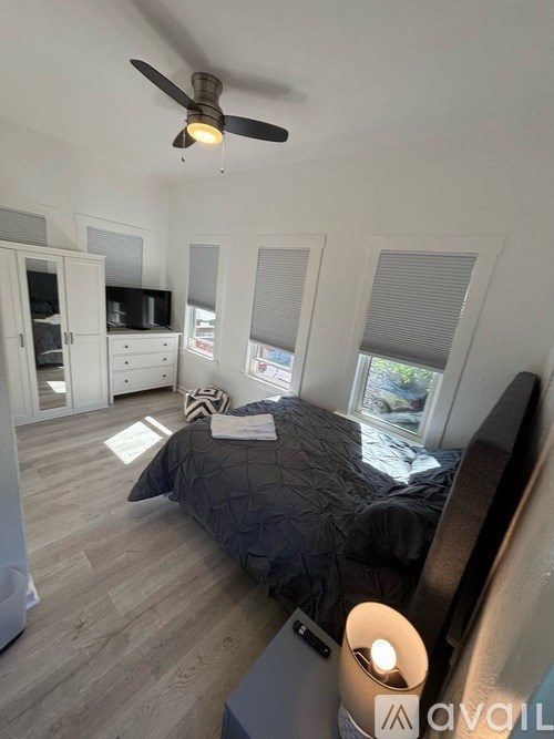 A bedroom with a bed, a ceiling fan, and a television.