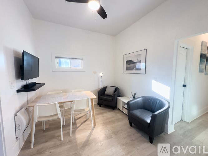 A living room with a black leather chair and a white table.