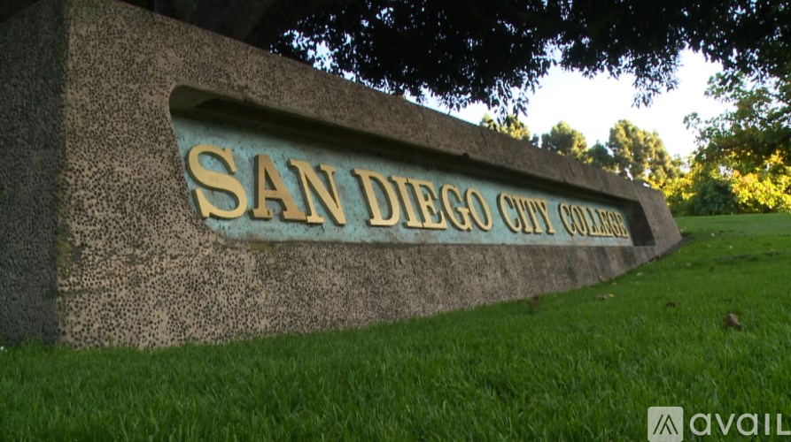A sign that says San Diego City College in gold letters on a stone wall.