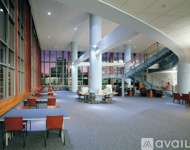 A spacious room with tables and chairs and a staircase.