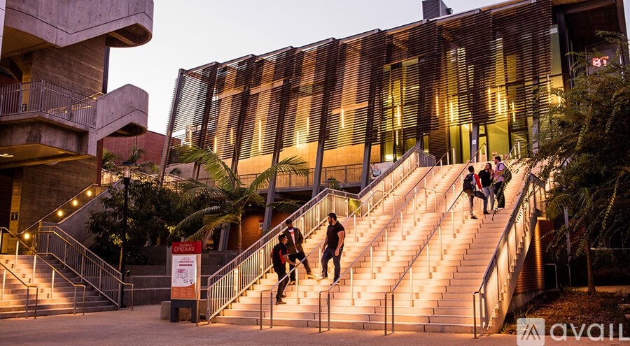 A group of people are walking up a flight of stairs outside a building with a modern design.