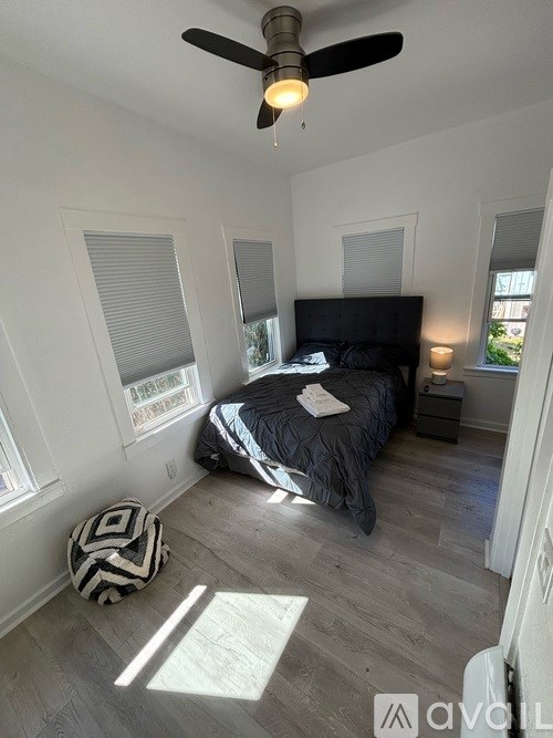 A bedroom with a bed, a ceiling fan, and a window with blinds.