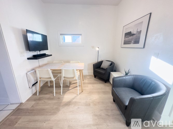 A living room with a grey couch, a white table, and a television on a stand.