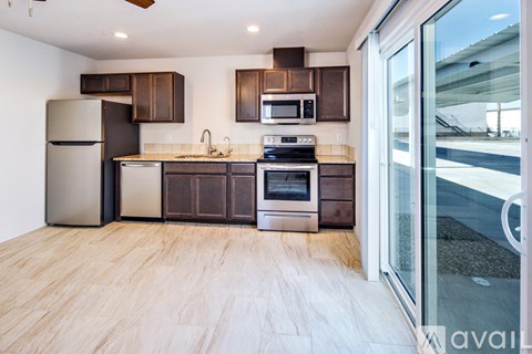 A kitchen with a refrigerator, microwave, oven, and sink.