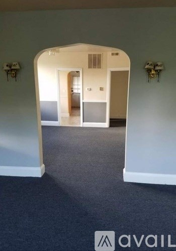 A hallway with a carpeted floor and white walls.