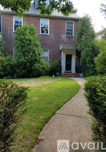 A brick house with a front yard and a sidewalk.