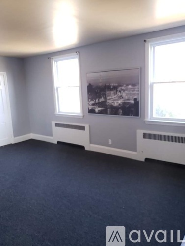 A room with a large window and a framed picture on the wall.