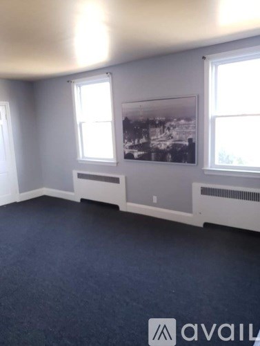 A room with a large window and a framed picture on the wall.