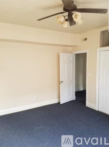 A room with a ceiling fan and a door leading to another room.