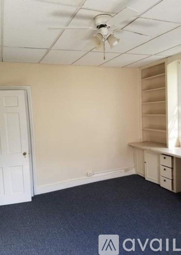 A room with a fan on the ceiling and a window with blinds.