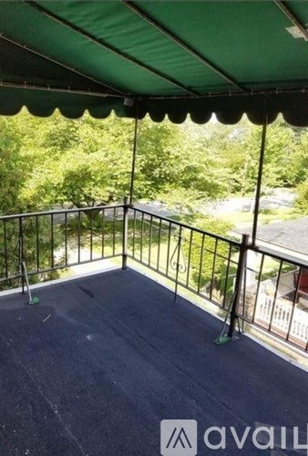 A balcony with a green canopy and a metal railing.
