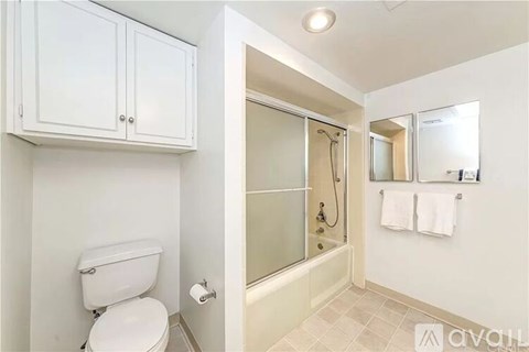 A white toilet sits next to a walk-in shower with a glass door.
