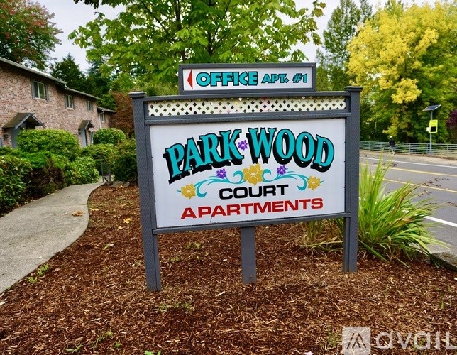 A sign for Park Wood Court Apartments is displayed in front of a building.