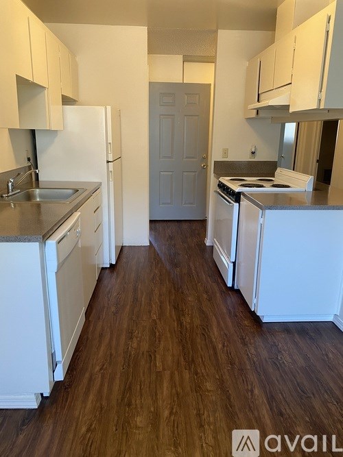 A kitchen with white appliances and wooden floors.