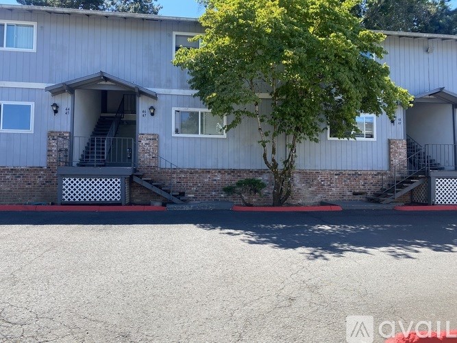 A tree in front of a building with a red brick wall and a black and white checkered gate.