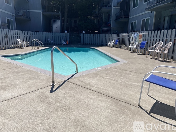 A pool surrounded by chairs and a fence.