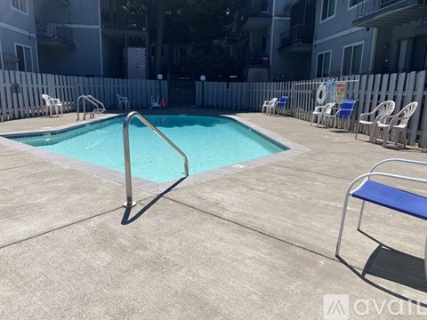 A pool surrounded by chairs and a fence.