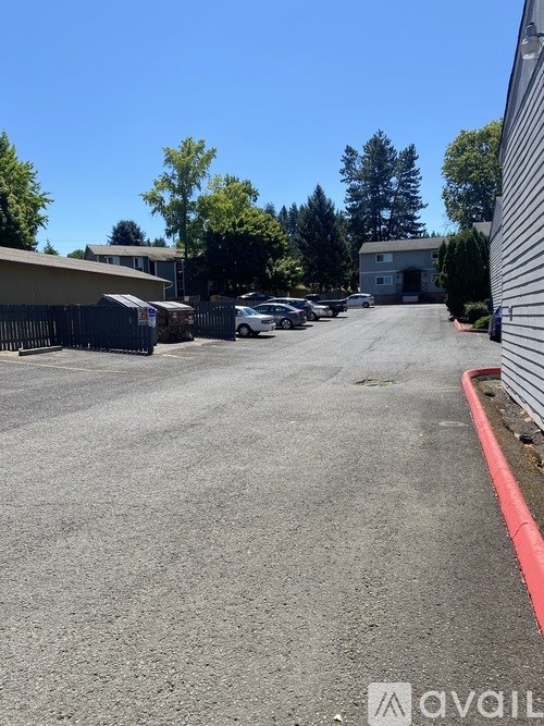 A parking lot with a red curb and a white car parked in the distance.