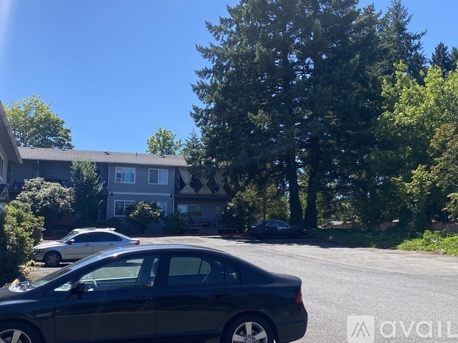 A black car is parked on the side of a road in front of a house.