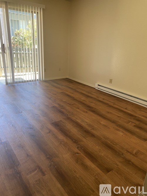 A room with wooden flooring and a sliding glass door.