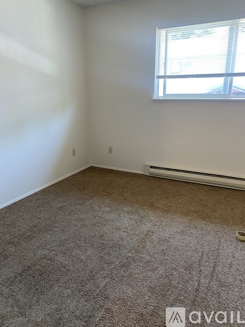 A carpeted room with a window and a wall-mounted air conditioner unit.