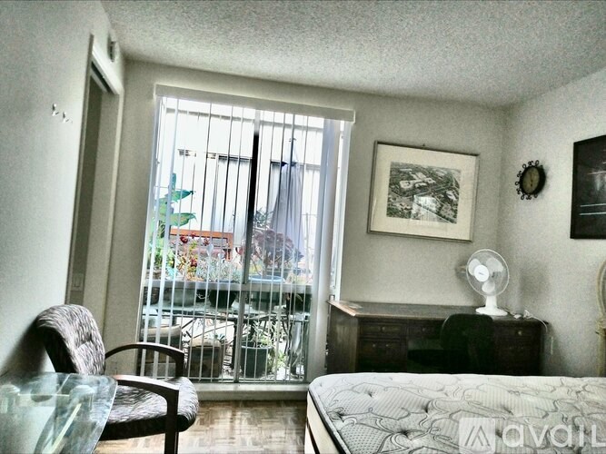 A bedroom with a bed, chair, and window.