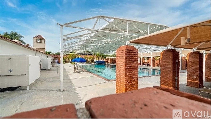 A pool area with a white building and a pool table.