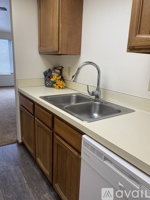 A kitchen with a white dishwasher and wooden cabinets.