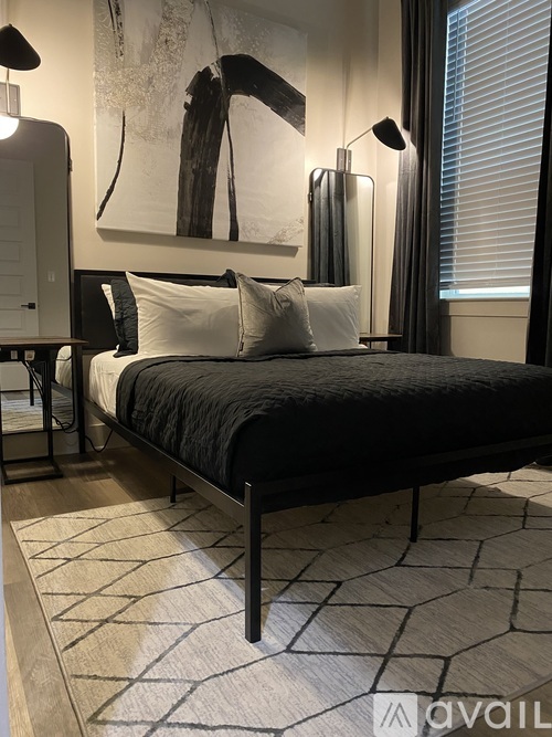 A bedroom with a large bed and a painting on the wall.