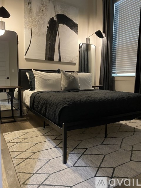 A bedroom with a large bed and a painting on the wall.
