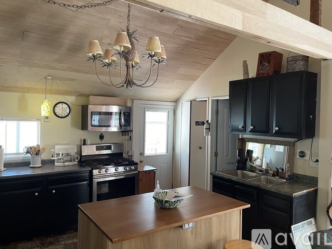 A kitchen with a wooden table and black cabinets.