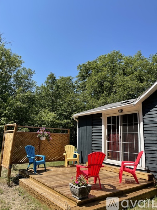 A small house with a deck and four chairs.