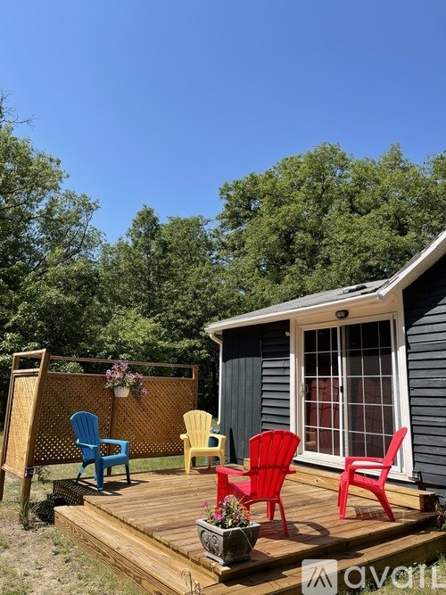 A small house with a deck and four chairs.